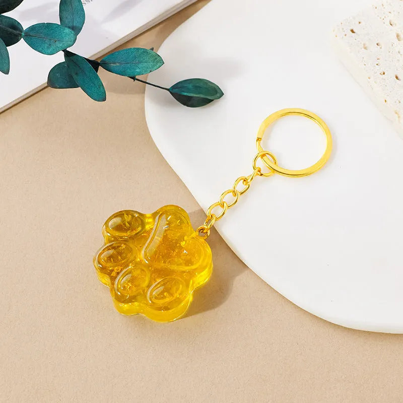 Small natural crystal cat's paw charm on a keyring, showing colour options including pink, red, blue, and purple gemstones.