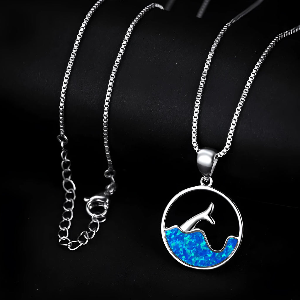 Close-up of a white gold plated sea fishtail pendant necklace with a round blue opal stone.