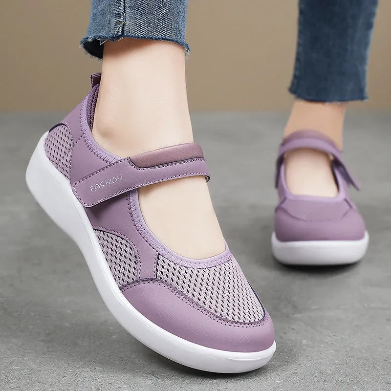 Women's low-top grey mesh sneakers with Velcro straps on a flat polyurethane sole.