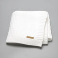 Solid colour infant blanket with textured lines, shown in a choice of colours including pink and beige.