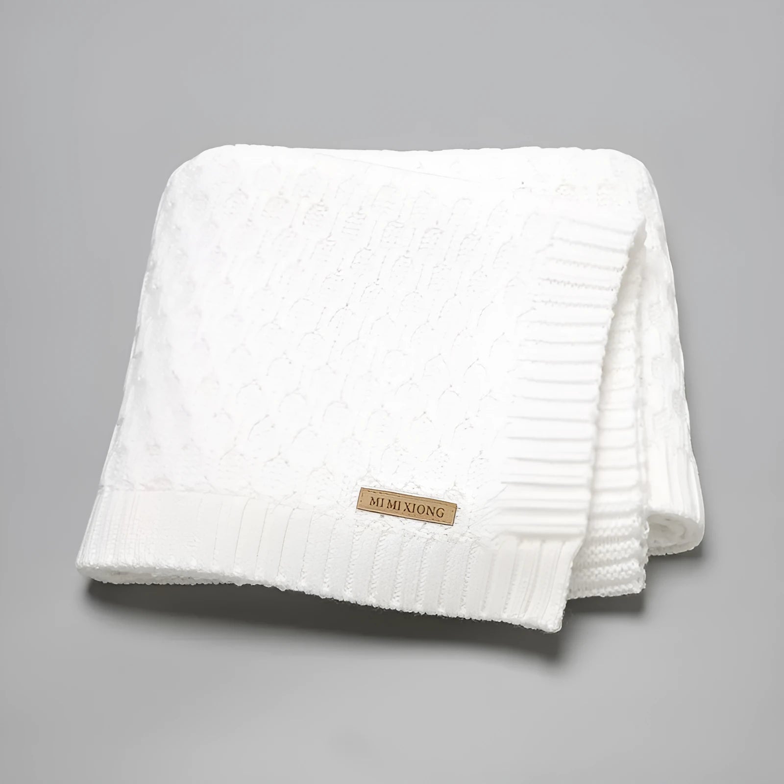 Solid colour infant blanket with textured lines, shown in a choice of colours including pink and beige.