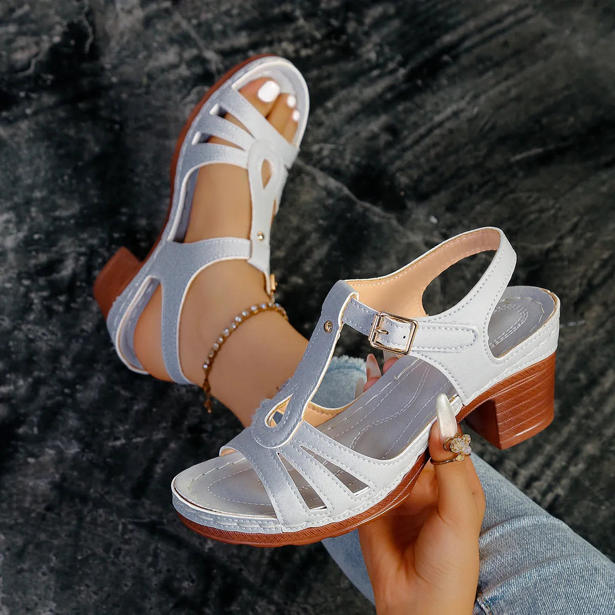 Women's black peep toe wedge platform sandals with a buckle fastening on a wooden surface.