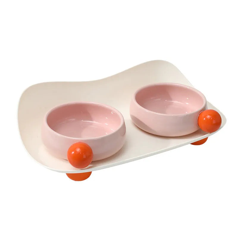 Raised ceramic double pet feeding bowl in pink, yellow, and pink yellow on a non-slip stand.