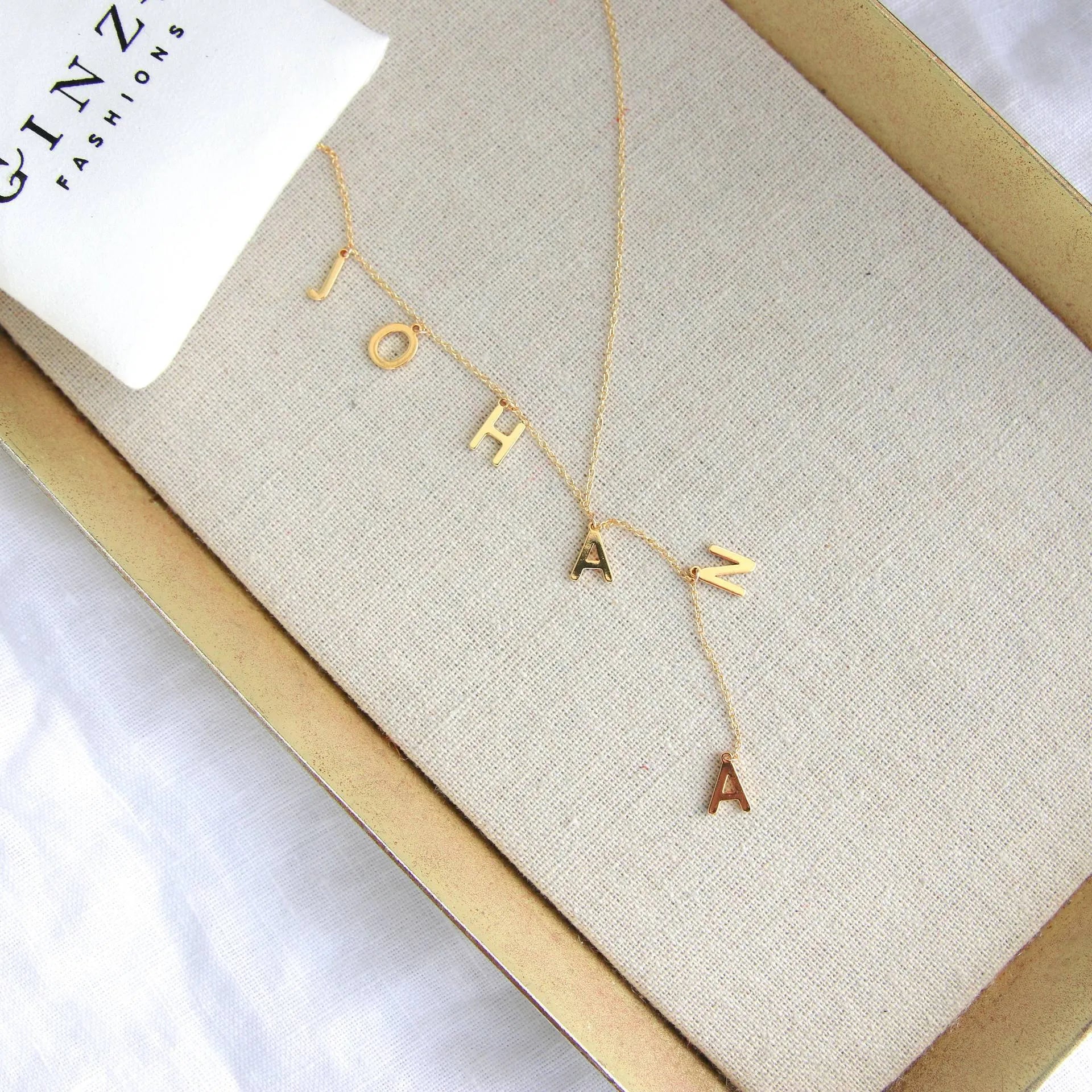 Gold lariat name necklace with bubble letters on adjustable chain, isolated on white background