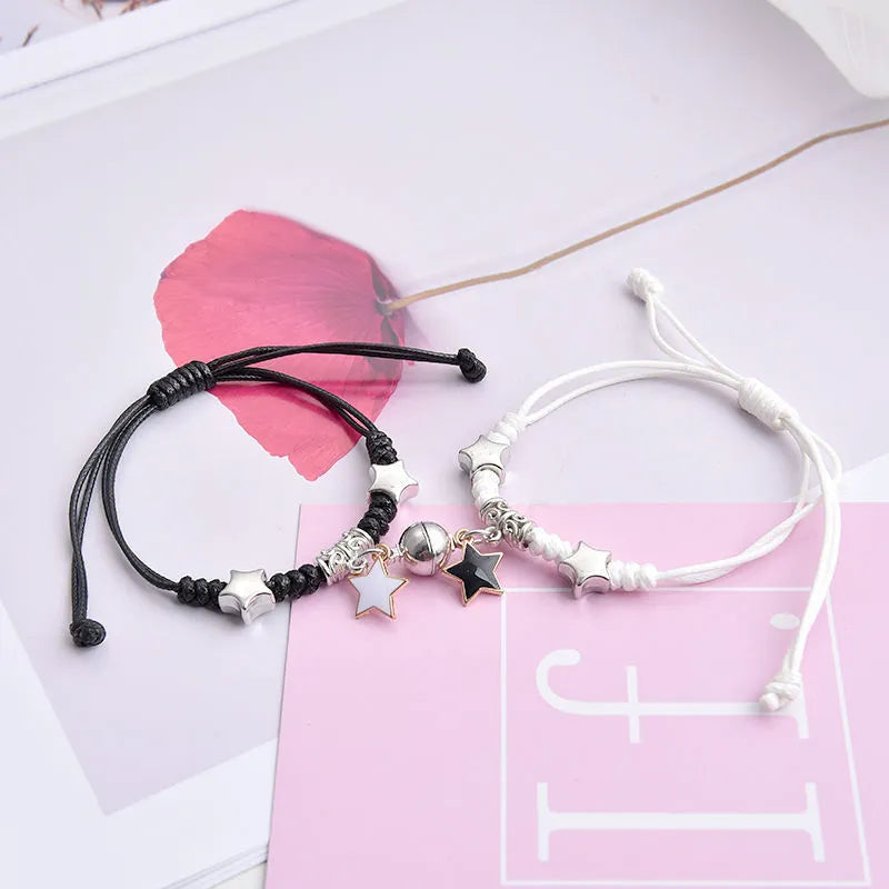 Pair of magnetic suction bracelets with alloy charms in various love and friendship themed designs on a wrist.