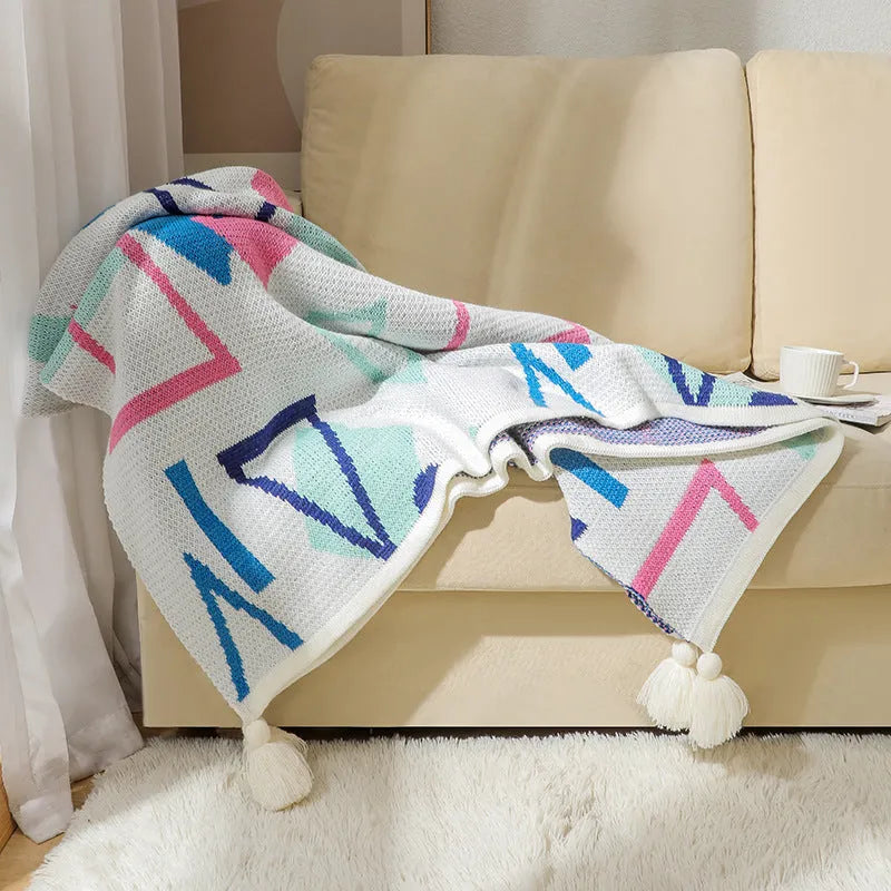 Acrylic sofa blanket with tassel fringe in geometric pattern, showing 130 cm width measurement