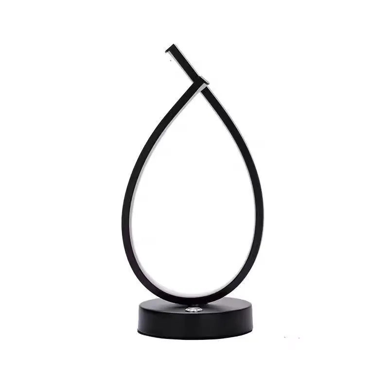 Black and white drop-shaped USB table lamp on a wooden desk.