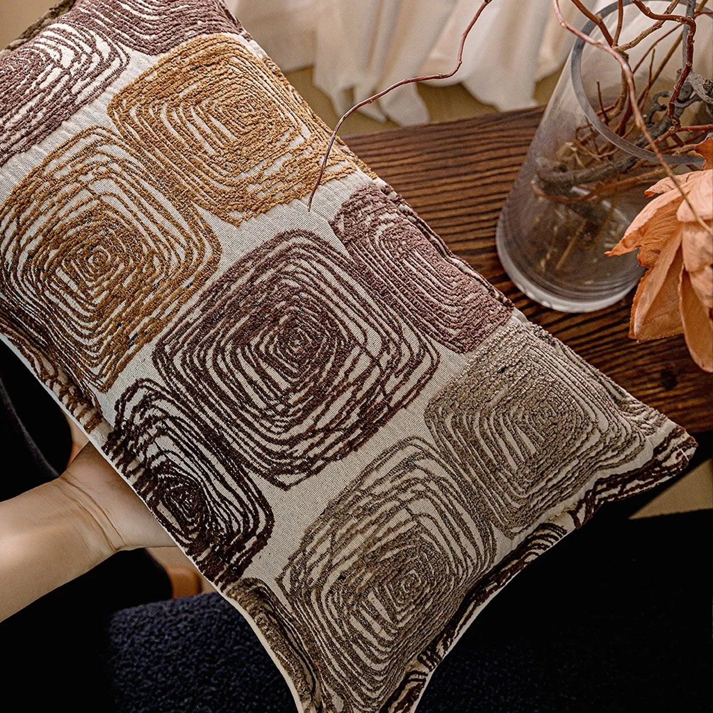 Abstract coil pattern pillow cover in cream and coffee colours on grey sofa