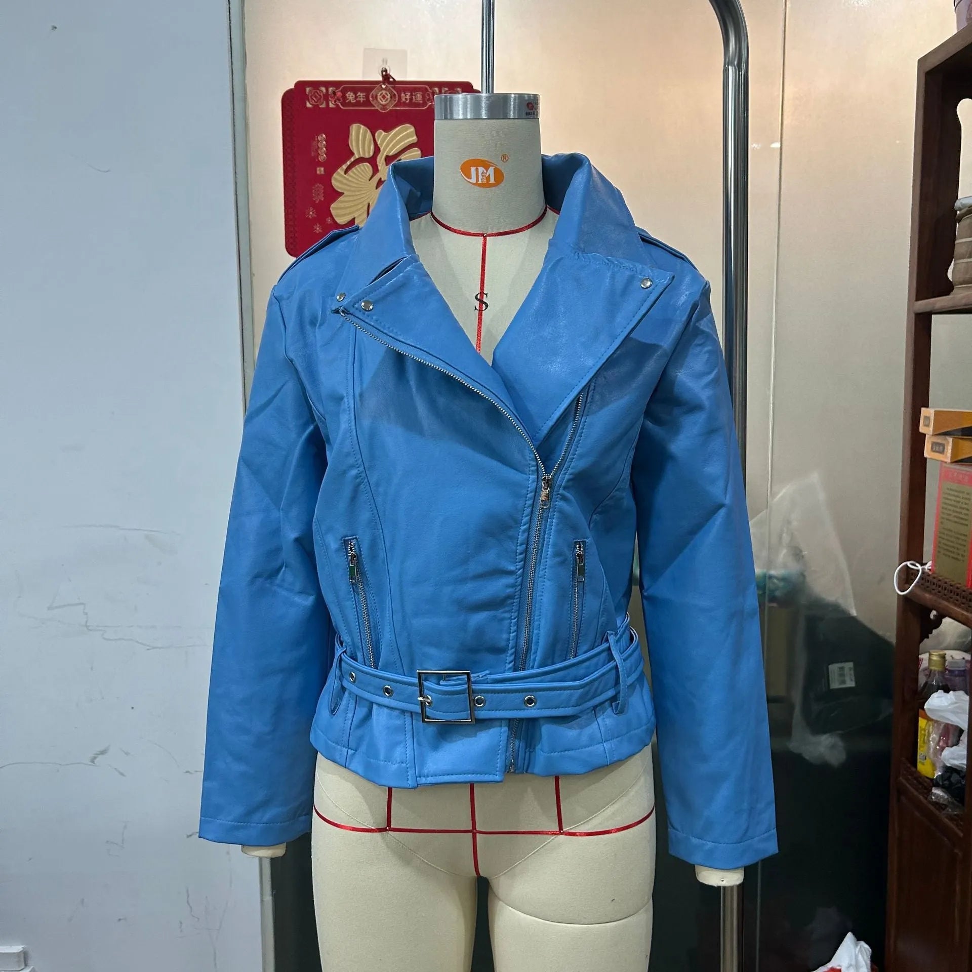 A black punk-style jacket with a lapel, short belt, and Peter Pan collar on a hanger.