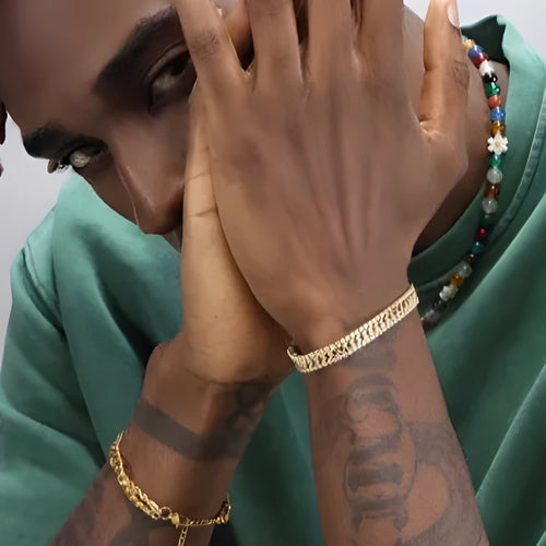 Gold coloured hip hop style tennis bracelet with stone inlay on a wrist.