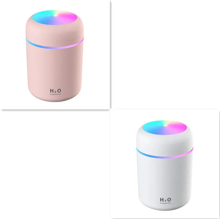 Pink USB desktop humidifier with LED lights and water tank on a wooden desk.