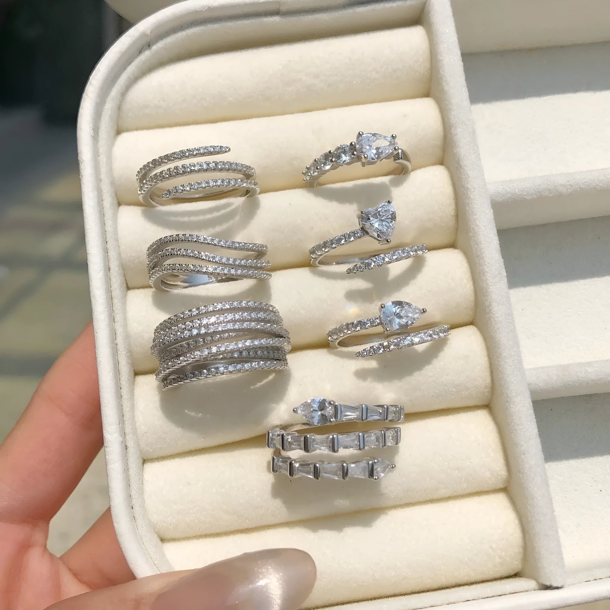 Silver ring with round zircon inlay, platinum colour, sits on a flat surface, side view