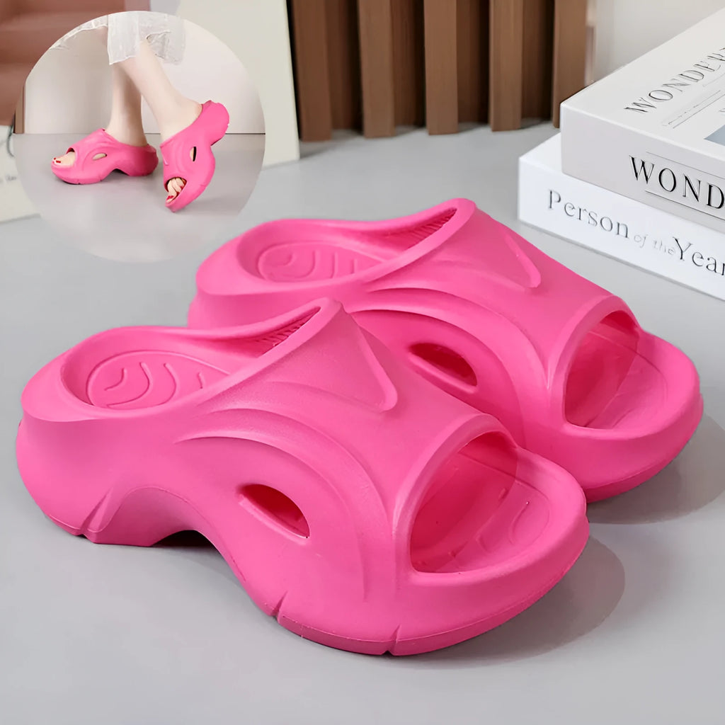 Women's thick-soled EVA slippers in rose red colour on a sandy beach.