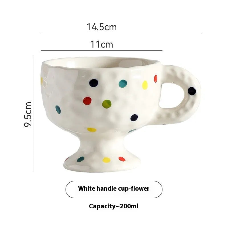 Hand-pinched irregularly shaped ceramic mug in a solid colour, shown on a table.