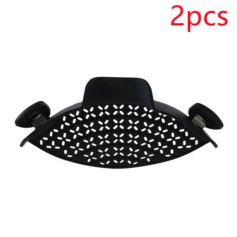 Silicone pot side drain stopper in black attached to saucepan rim with leak-proof edge