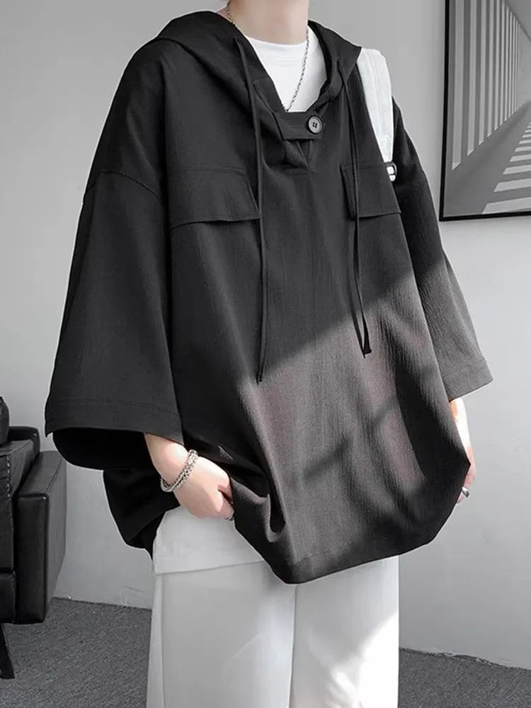 A man wearing a loose-fit black hooded short sleeve t-shirt made of polyester for summer.