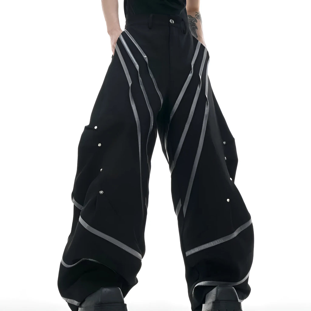 Men's black trousers with three-dimensional cut and silver metal rivet pleat detailing.