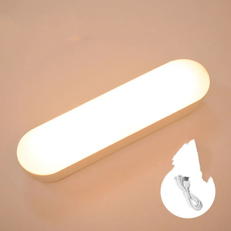 Fully automatic unplugged bedside night light for dormitory with magnetic base, USB rechargeable, showing yellow light mode on a dark bedside table