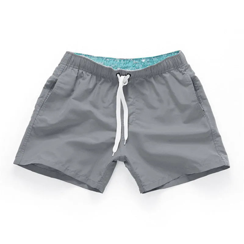 Men's black surf shorts made from polyester fabric with a straight leg opening, shown on a size chart.