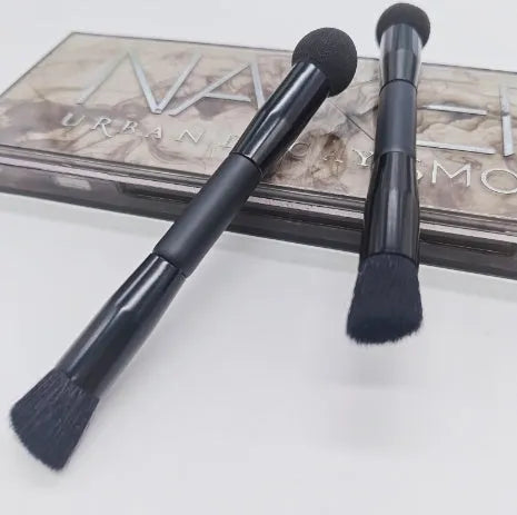 Double-headed black makeup brush with a pointed concealer brush on one end and an angled sponge on the other.