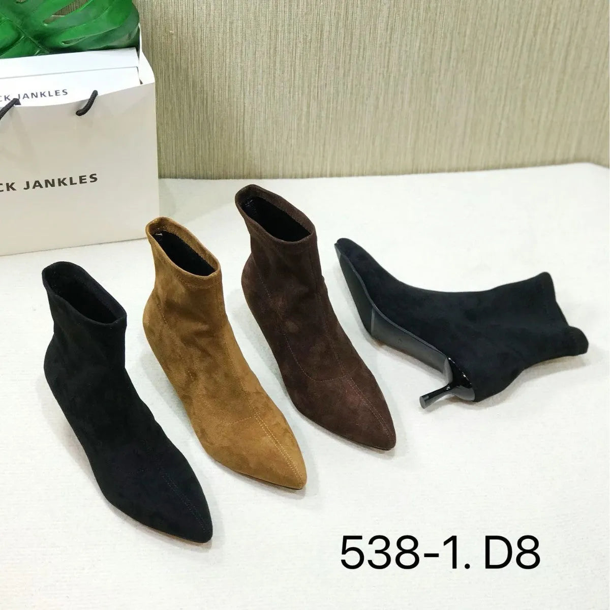Black pointed toe women's ankle boots with stiletto heels on a neutral background.