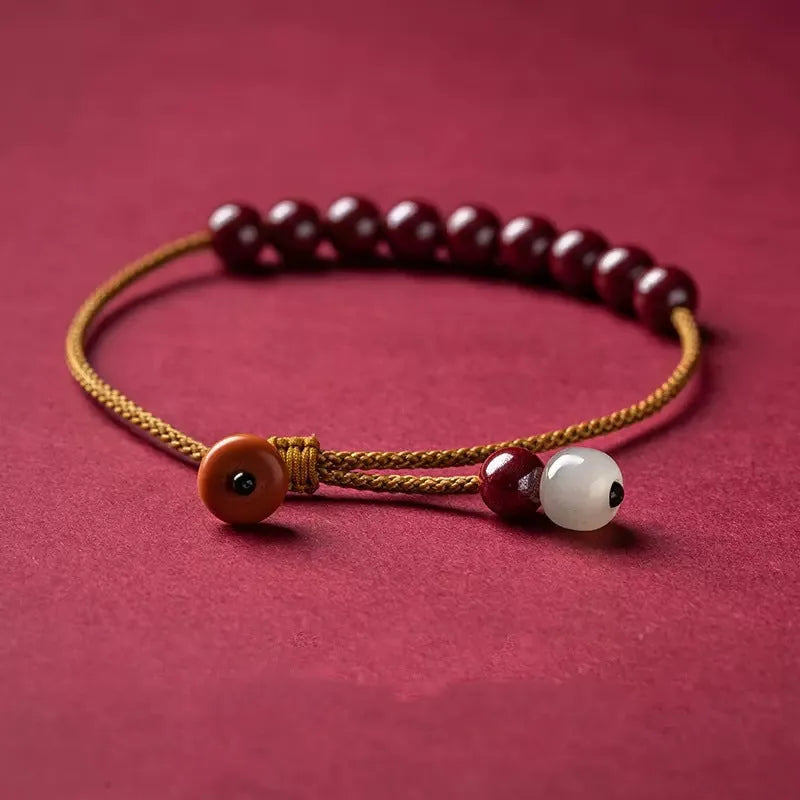 Hand-woven geometric bracelet made from raw Cinnabar and Hetian Jade ore on a wrist.
