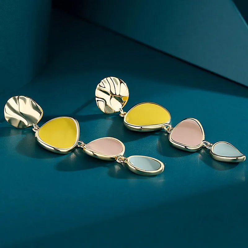 A pair of thin sterling silver stud earrings with Morandi-coloured wafer discs featuring an oil-drip texture.