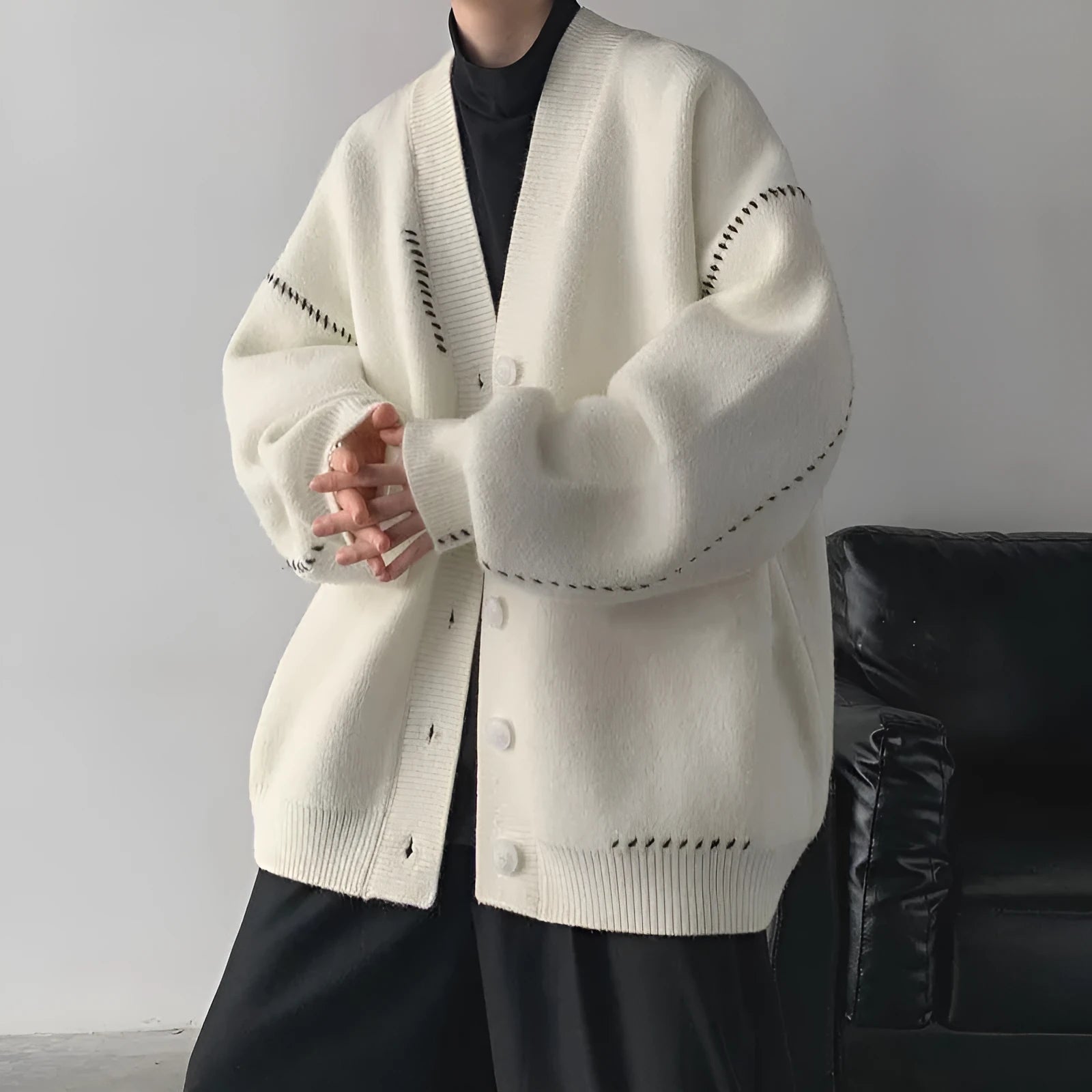 Women's loose fit black knitted cardigan coat with long sleeves on a hanger.
