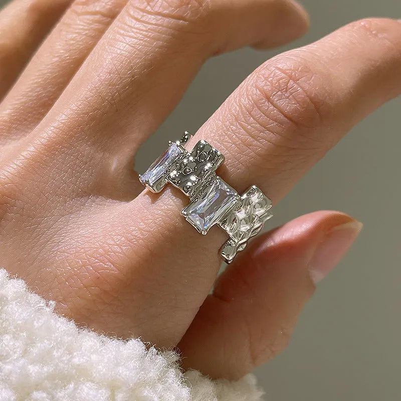 Silver geometric open ring with cross design and zircon decoration on white background