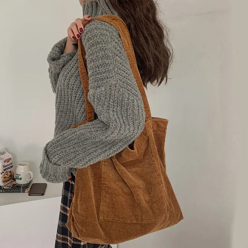Large corduroy tote bag with soft handle, pleated detailing, and interior zipper pocket. Colour: black.