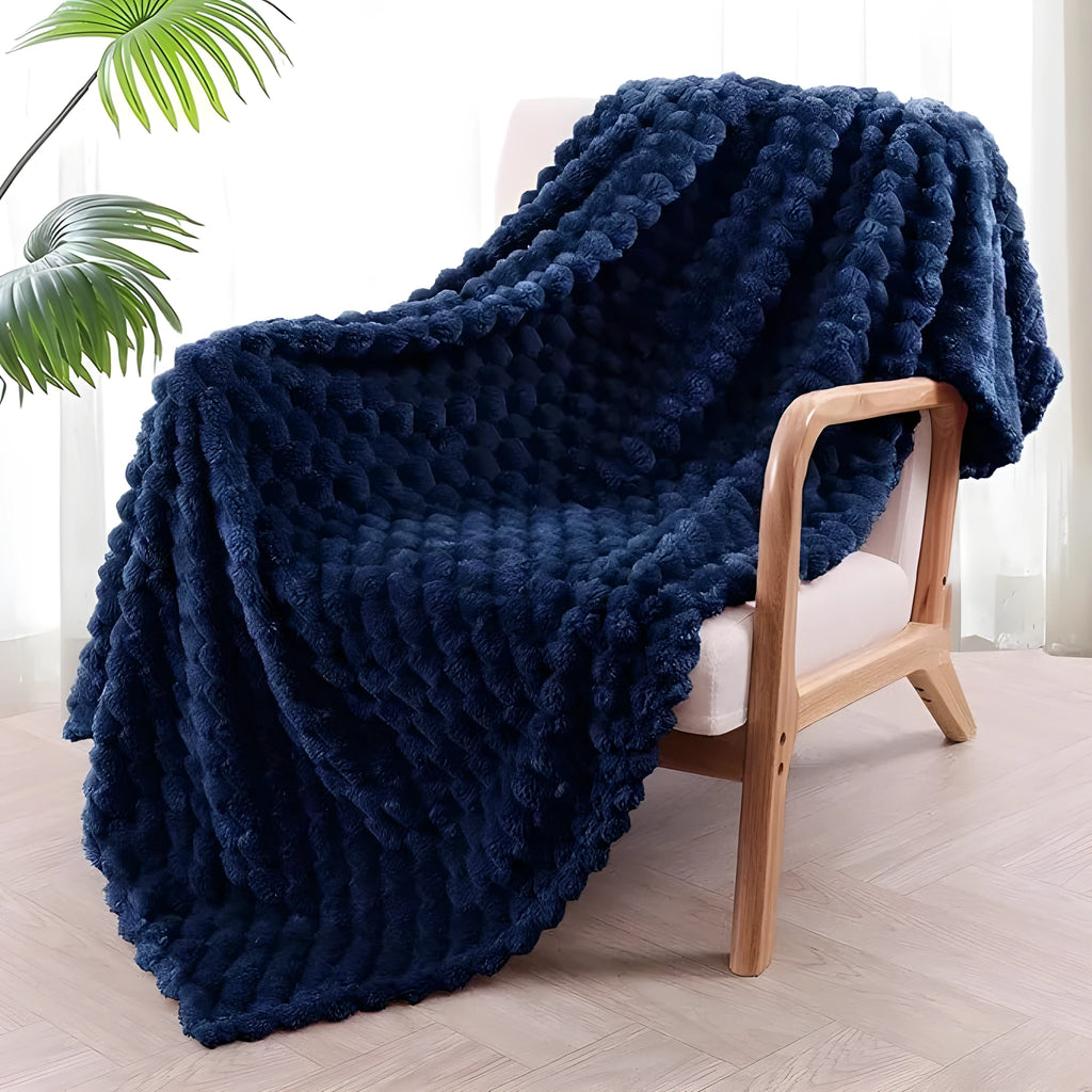 Soft camel-coloured plaid fleece blanket for children folded on a bed.