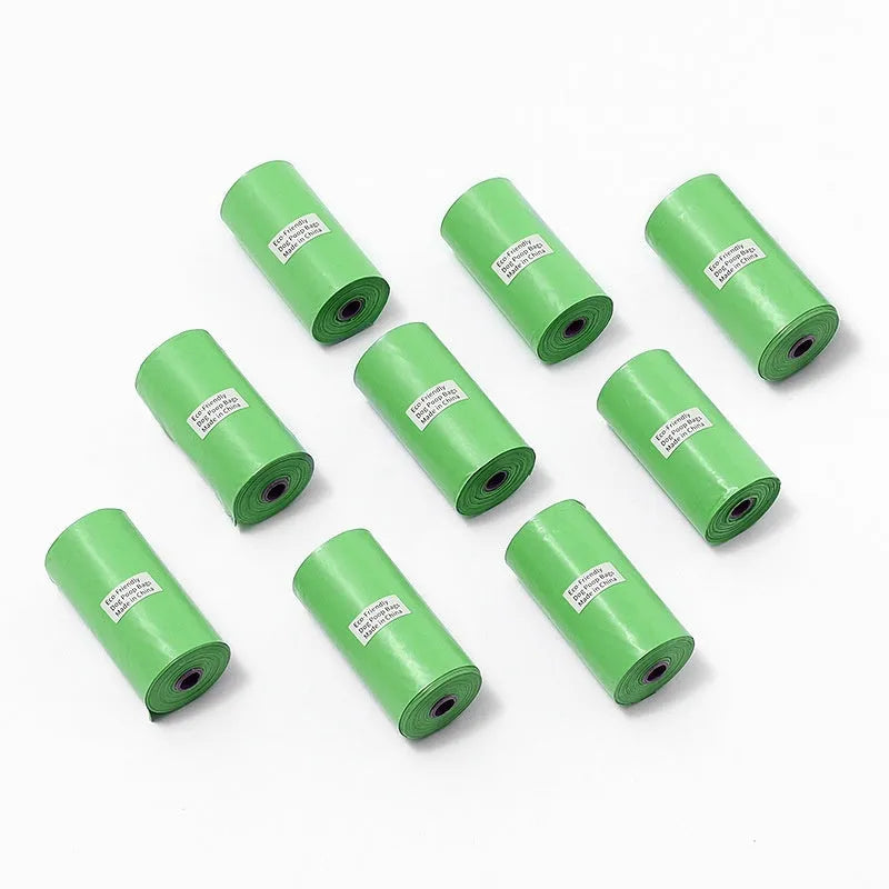 Roll of green EPI degradable dog poo bags next to a white plastic dispenser on a grass background.