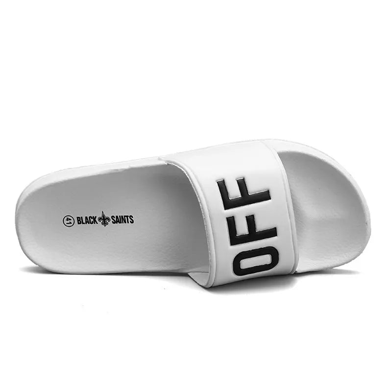 Men's black open toe slippers with a rubber sole on a wooden floor.