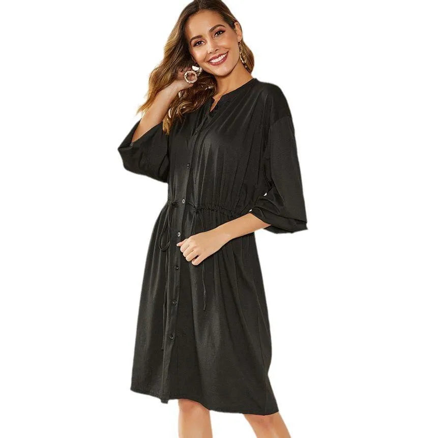 A woman wearing a solid colour A-line midi dress with an elastic waist, an attached belt, and long sleeves.