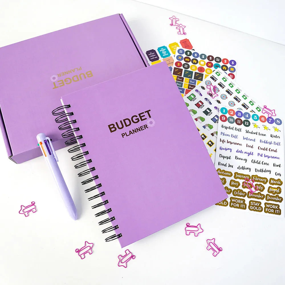 Purple coil-bound financial planning notebook with budgeting stickers and paper clips for monthly expense tracking