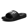 Men's black open toe slippers with a rubber sole on a wooden floor.