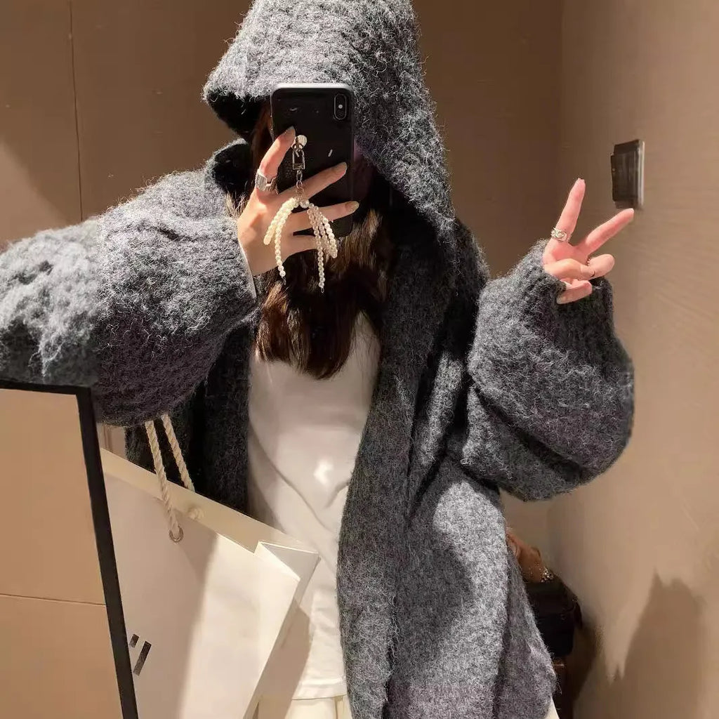 Woman wearing a loose-fit, chunky knit hooded cardigan in a macaron colour.