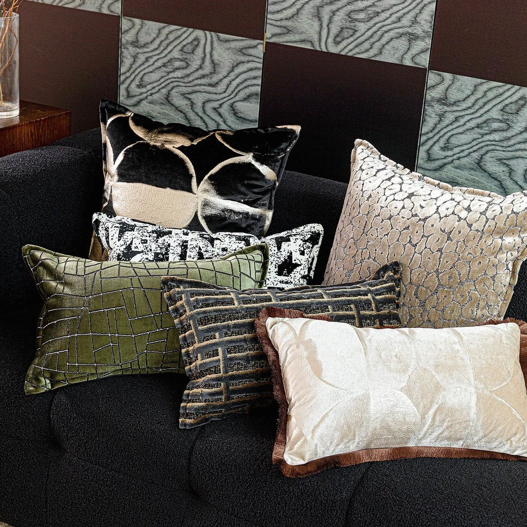 Black and gold abstract pattern decorative velvet cushion on a grey sofa.