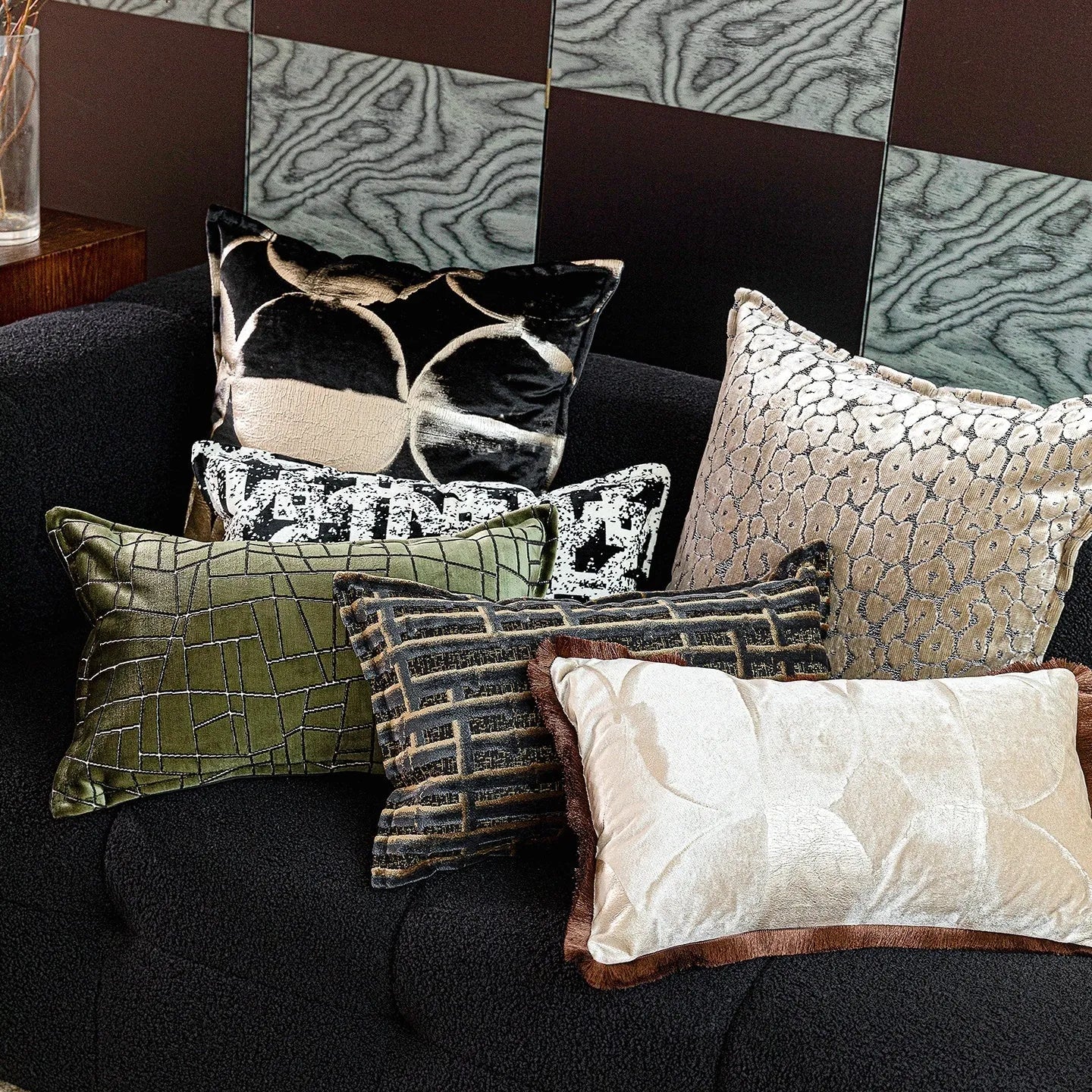 Black and gold abstract pattern decorative velvet cushion on a grey sofa.