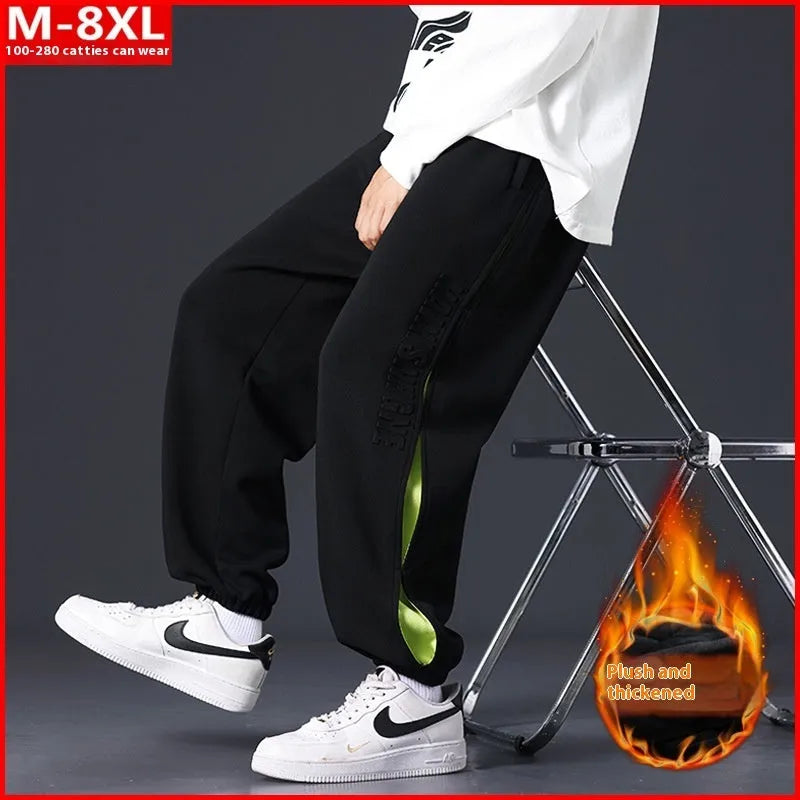 Men's loose black cotton trousers with white collage stitching print and banded ankle cuffs laid flat.