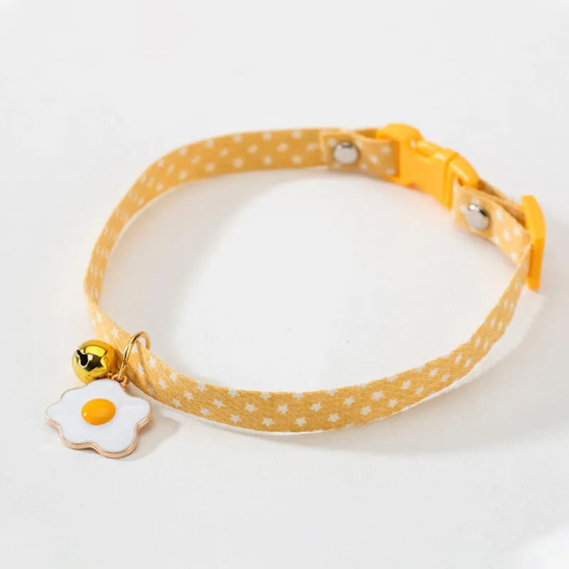 Green adjustable pet collar with a metal bell pendant and a matching bow tie on a white background.