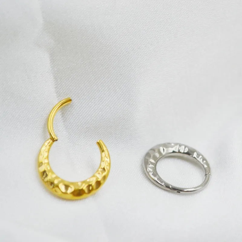 Close-up of a titanium concave-convex nose ring in gold finish, showing its textured profile and 1.2mm thickness.