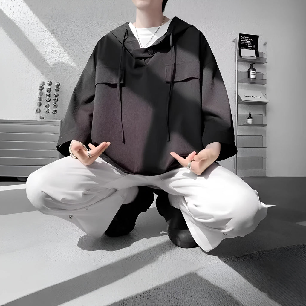 A man wearing a loose-fit black hooded short sleeve t-shirt made of polyester for summer.