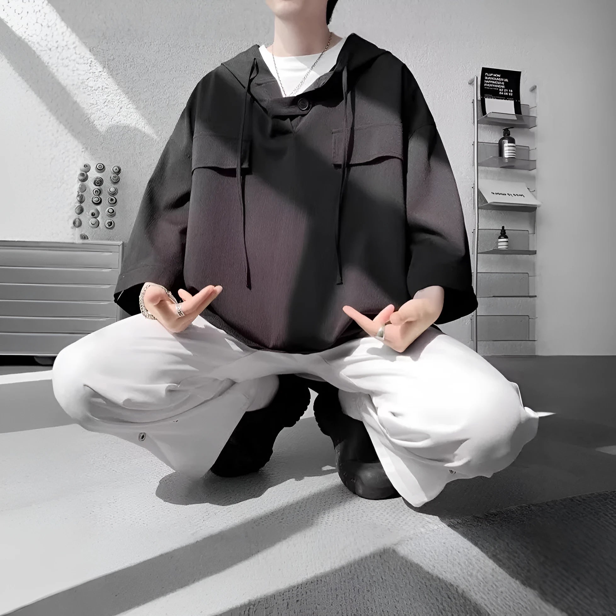 A man wearing a loose-fit black hooded short sleeve t-shirt made of polyester for summer.