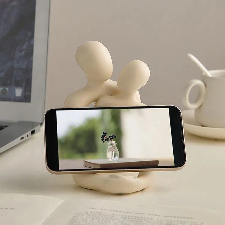 Modern style resin statue of a couple in milky white or gold colour on a wooden surface.