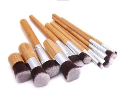 11 bamboo handle makeup brushes arranged on linen bag, including foundation blush and eye shadow brushes