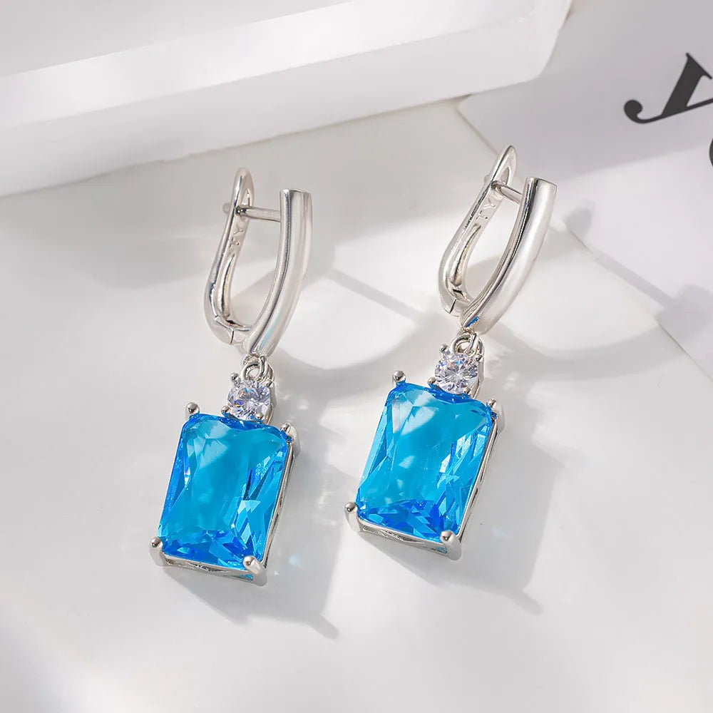 A pair of square-shaped gold-coloured electroplated earrings on a flat surface.
