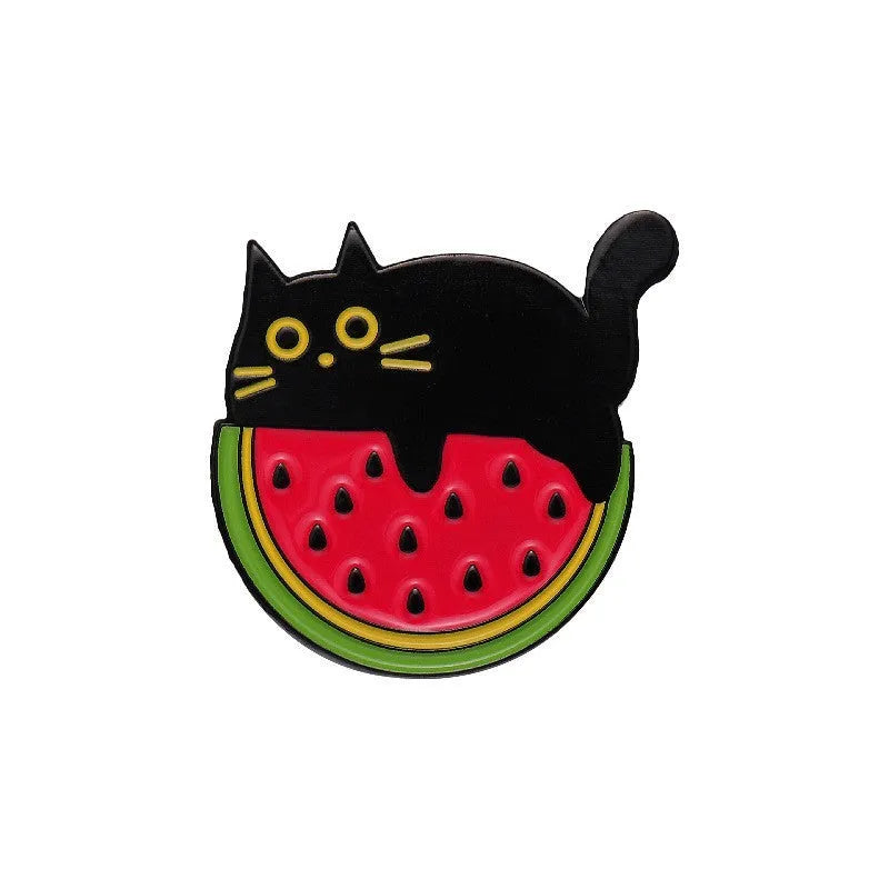 Colourful cartoon fruit and letter design metal brooch on a fabric background.