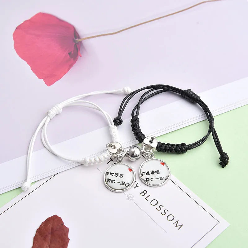 Pair of magnetic suction bracelets with alloy charms in various love and friendship themed designs on a wrist.