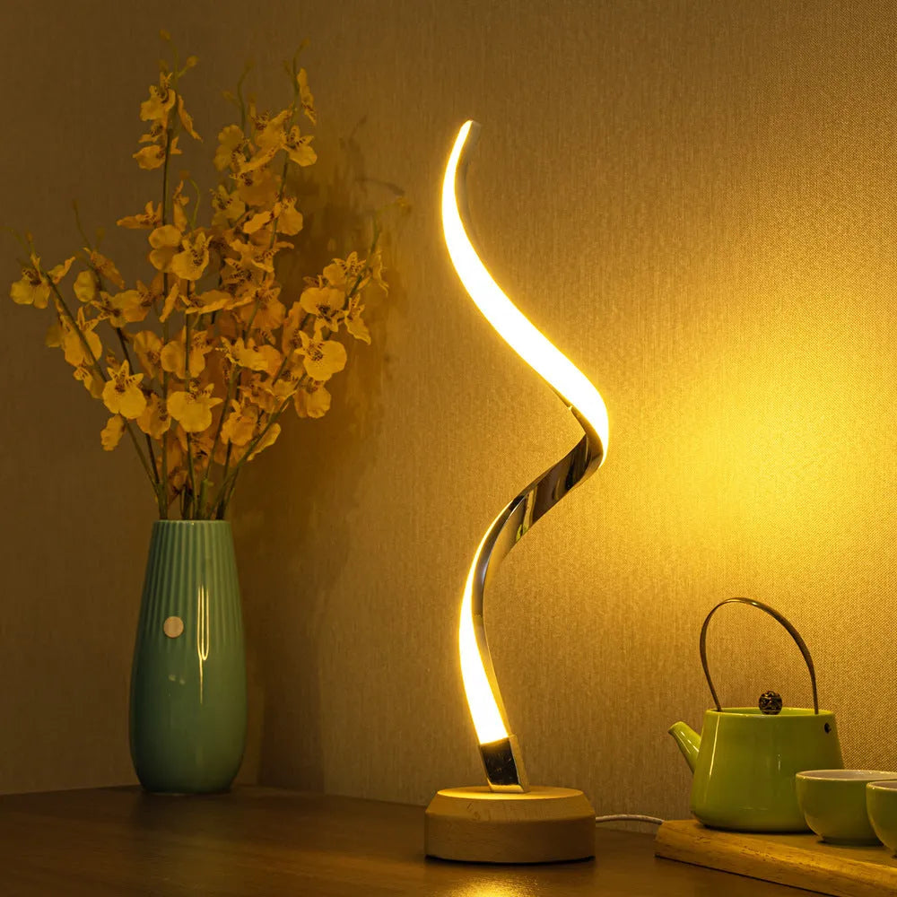 LED spiral table lamp with wooden curved base and USB cable, glowing warm white light